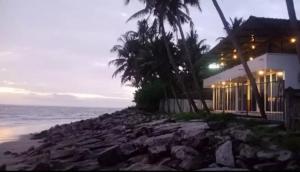a house on the beach with palm trees and the ocean at QUILON BEACH Inn in Kollam