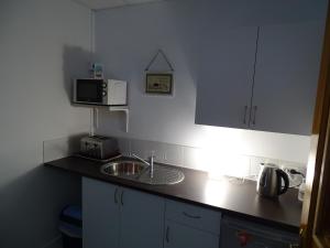 a small kitchen with a sink and a microwave at Rickaty Lodge Bed and Breakfast, 2 star Hotel, Plane spotting Hotel, Gran Canaria Airport LPA, Gran Canaria, Spain in Las Puntillas