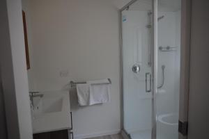a white bathroom with a shower and a sink at Lazy Daze in Wanaka +6 photos