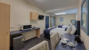 a hotel room with two beds and a table with a dining room at Border Motel in Goondiwindi