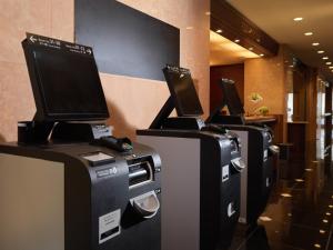 a row of computer monitors on display in a lobby at Hotel Emisia Tokyo Tachikawa in Tachikawa