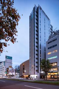 a tall white building on a city street at night at Hotel Emisia Tokyo Tachikawa in Tachikawa