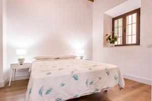 a white bedroom with a bed and a window at Stunning apartment in central Seville in Seville