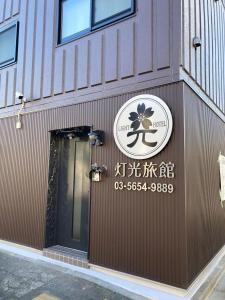 un panneau sur le côté d'un bâtiment avec une porte dans l'établissement 灯光旅館 Light hotel, à Tokyo