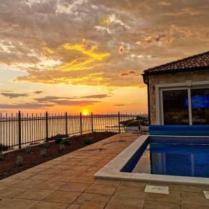 puesta de sol sobre el agua con piscina en Vista Villas - Sweet Life Apartment Villa S, en Ražanac