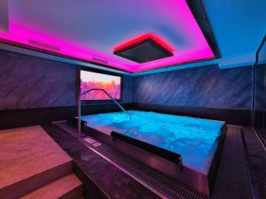 Alpen Appartements Lärchenhof في ليرموس: حوض استحمام ساخن في غرفة مع أضواء وردية