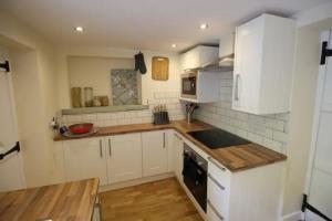una cucina con armadi bianchi e ripiano in legno di Cosy Crickhowell Cottage a Crickhowell