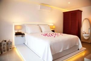 - une chambre avec un lit blanc orné de fleurs roses dans l'établissement PAYAM BUTİK OTEL, à Datça