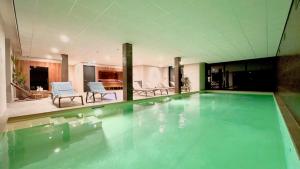 a large swimming pool in a building with chairs at Duinhotel Breezand in Vrouwenpolder
