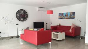 a living room with two red chairs and a clock at Villa Tauro Beach & Golf in La Playa de Tauro