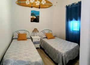 two beds in a room with a surfboard on the wall at Casa Trini in La Mareta