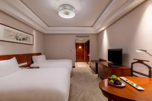 um quarto de hotel com duas camas e uma mesa com uma tigela de fruta em Sofitel Hangzhou Westlake em Hangzhou