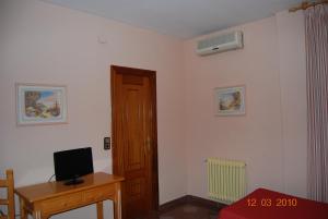 a room with a desk with a television and a door at Hotel Vista Nevada in Darro