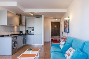 a living room with a blue couch and a kitchen at Sunset in paradise in El Cotillo