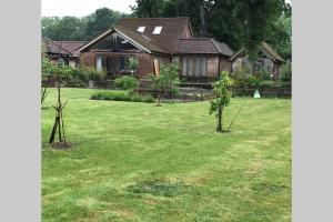 a house with a yard with two small trees at 4 Kingsize Beds Ensuite - Sleeps 8-10 - Rural Contemporary Oak Framed House in Chiddingfold