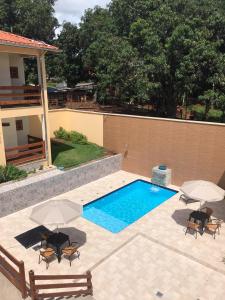 una piscina con sillas y sombrillas junto a un edificio en Pousada Morro do Frota, en Pirenópolis