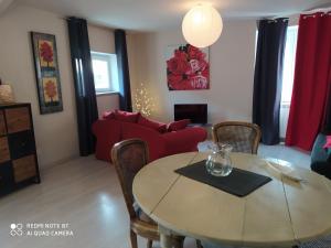 uma sala de estar com uma mesa e um sofá vermelho em Gîte Les Gorges du Tarn em La Cresse