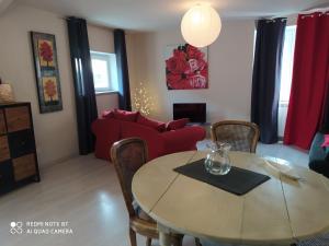 a living room with a table and a red couch at Gîte Les Gorges du Tarn in La Cresse