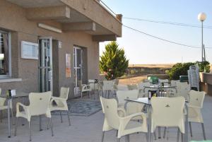 a patio with white chairs and tables and a building at Hotel Vista Nevada in Darro