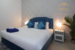 a bedroom with a large bed with blue pillows at New Arabian Holiday Homes - Escan Tower in Dubai