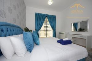 a bedroom with a large white bed with blue pillows at New Arabian Holiday Homes - Escan Tower in Dubai