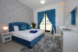 a bedroom with a blue bed and a desk and a window at New Arabian Holiday Homes - Escan Tower in Dubai