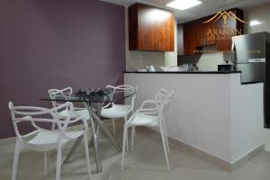 a kitchen with a glass table and white chairs at New Arabian Holiday Homes - Escan Tower in Dubai