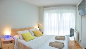 Un dormitorio con una cama con almohadas amarillas y una ventana en Peregrina Pensión 2, en O Pedrouzo