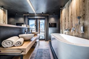 a bathroom with a large tub and two sinks at ALMMONTE PRÄCLARUM SUITES Design Hotel in Wagrain
