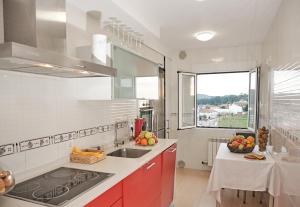 una cucina con armadi rossi, lavandino e finestra di Peregrina Pensión 2 a O Pedrouzo