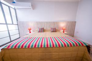 Un dormitorio con una cama grande con una manta de rayas de colores. en Augusta en Salta