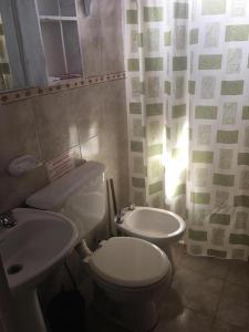 a bathroom with a white toilet and a sink at Cabañas y Posada La Vertiente in Los Reartes