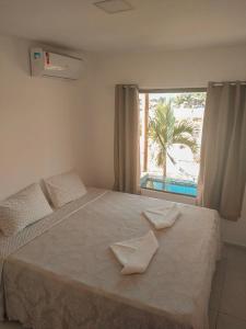 a bedroom with a large bed with a window at Bellíssimo Villaggio in Porto De Galinhas