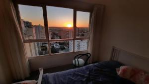a bedroom with a bed and a window with the sunset at Miramar con Vista al mar in Miramar
