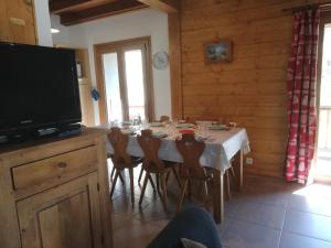 a dining room with a table with chairs and a television at crocus in Saint-Martin-de-Belleville