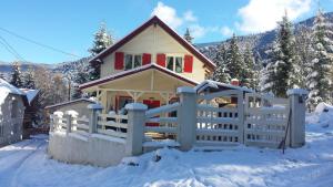 een huis met een wit hek in de sneeuw bij Casa Eggo in Rausor