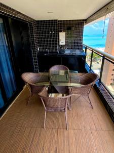 d'un balcon avec une table et des chaises en verre ainsi qu'un piano. dans l'établissement Landscape Beira Mar Meireles, à Fortaleza