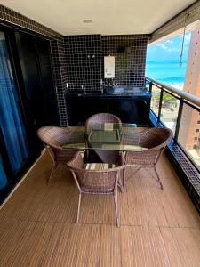 uma varanda com uma mesa e cadeiras de vidro e um piano em Landscape Beira Mar Meireles em Fortaleza