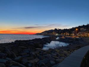 une plage avec des rochers et un coucher de soleil en arrière-plan dans l'établissement Appartamento Vista mare con Piscina Cala di Sole, à Imperia