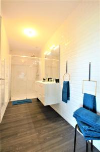 La salle de bains blanche est pourvue d'une douche et d'une chaise bleue. dans l'établissement Les Bois de Champagne L'industriel, à Magnant