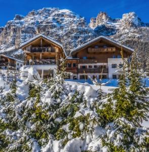 un hotel con montañas cubiertas de nieve en el fondo en Ciasa Rosra, en La Villa