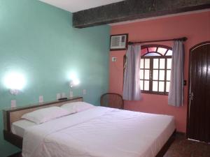 a bedroom with a large white bed with a window at Pousada Flamingo in Búzios