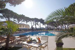 un complejo de piscina con mesas, sillas y palmeras en Park Hotel Maracaibo, en Lido di Jesolo