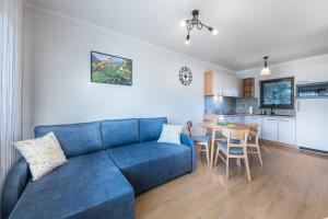 a living room with a blue couch and a kitchen at Apartamenty ARNIKA in Jurgów
