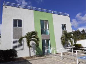 biało-zielony budynek z palmami przed nim w obiekcie Lindo Flat em Ponta Negra - Natal w mieście Natal