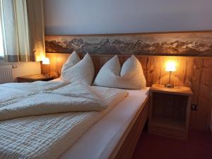 - une chambre dotée d'un lit blanc avec des oreillers et des lampes dans l'établissement Apart Bella Mira, à Samnaun