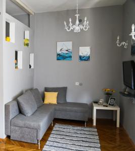 a living room with a gray couch and a chandelier at Apartment Mia in Skopje
