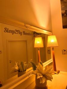 a bedroom with a mirror and a lamp and flowers at Sleep2Fly Hamburg-Airport in Hamburg