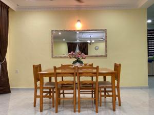 a dining room with a table and chairs and a mirror at Hanna Homestay Kangar in Kangar