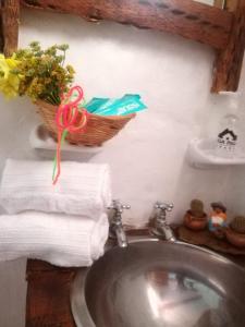 a bathroom sink with towels and a basket of flowers at Cabañas Paqa Paqa in Maimará